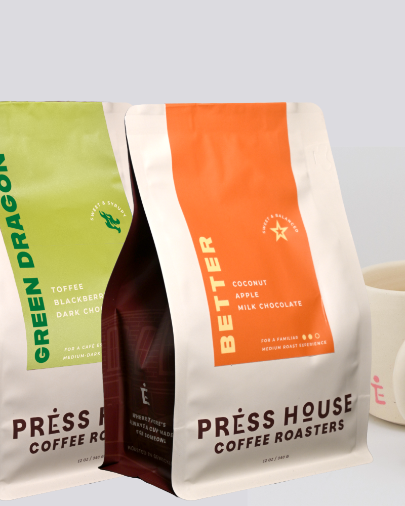 Two coffee bags from Press House Coffee Roasters with two mugs on a light gray background